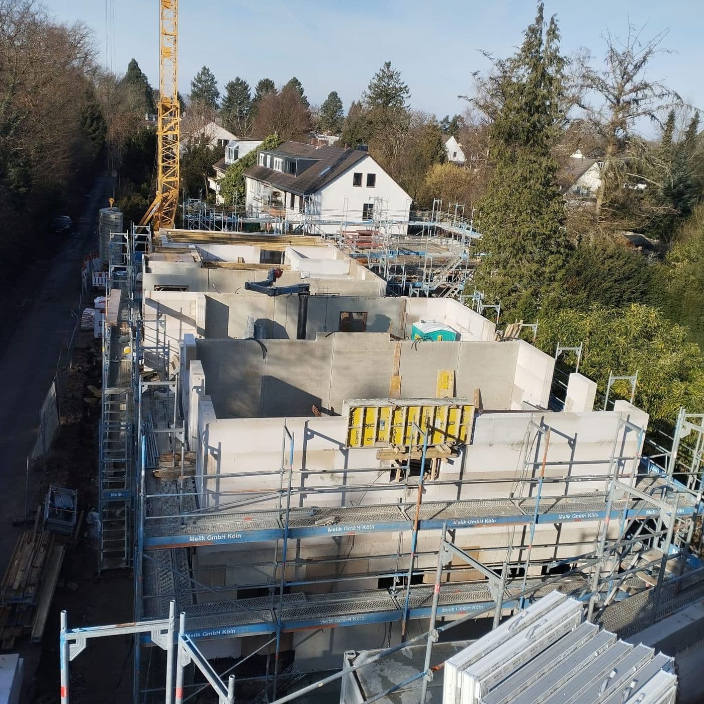 Luftaufnahme einer Rohbaustelle mit Kran, Gerüst und Kellerwänden